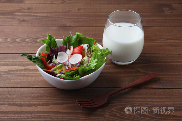 新鲜的蔬菜沙拉碗里放着牛奶放在木桌上