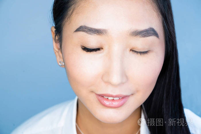一位美丽的亚洲女性在睫毛延伸过程中闭上眼睛的肖像前后双倍睫毛量