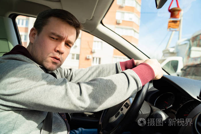 一个穿着灰色毛衣的伤心人在汽车的方向盘后面