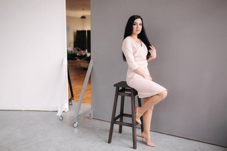 Elegant brunette woman in stylish dress posing in studio on gray