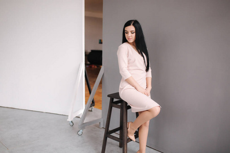 Elegant brunette woman in stylish dress posing in studio on gray