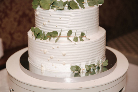 美丽的白色婚礼蛋糕，绿叶装饰