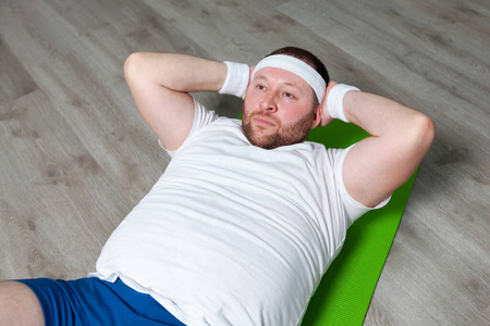 胖子躺在健身馆地板上的绿色垫子上,用最后的力气锻炼腹部肌肉.