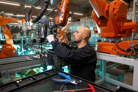 在汽车工业，智能工厂里，工程师对一个自动机械手臂进行维护