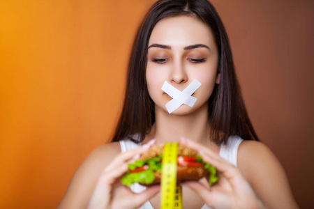 节食的概念可爱的女人密封嘴保持油腻汉堡照片