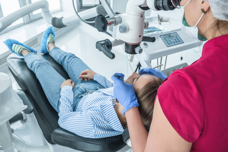 牙医医生在显微镜下看病人的牙齿