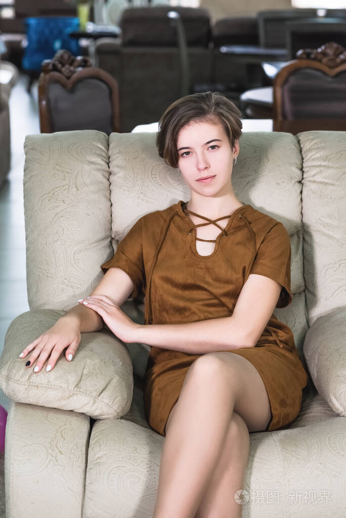 一个年轻漂亮的女孩坐在一张漂亮的昂贵的椅子上