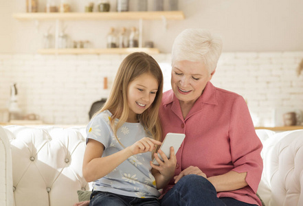 成熟女人在家陪孙女玩智能手机游戏