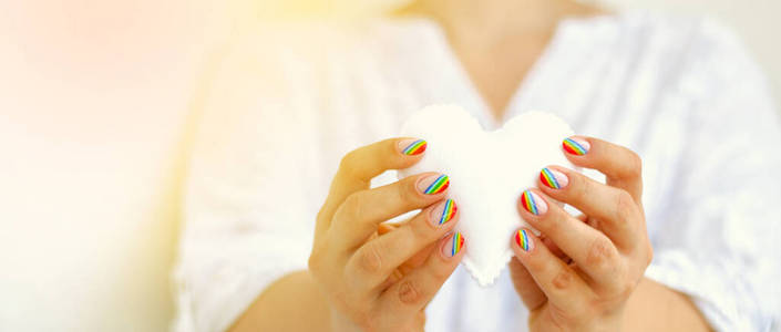白色毡心在女性手中彩虹修指甲.爱情,情人节,同性恋,骄傲的概念照片