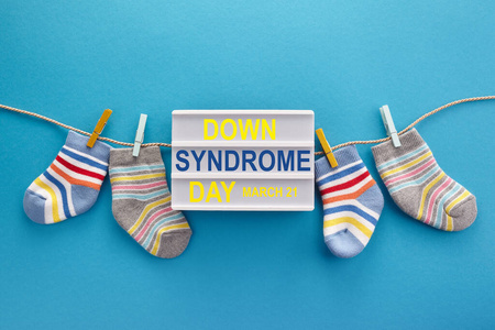世界唐氏综合症日背景。唐氏综合症意识概念。蓝色背景的袜子和灯箱