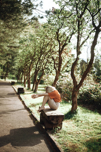 美丽的女人坐在户外的长椅上，放松着。柔和的绿色。公园
