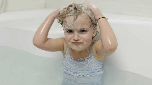 泳装小孩可爱的金发女孩穿着泳装洗澡.小孩洗头照片