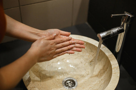 在公共场所的浴室里用肥皂洗手的女人。小心洗手，防止致病病毒和细菌