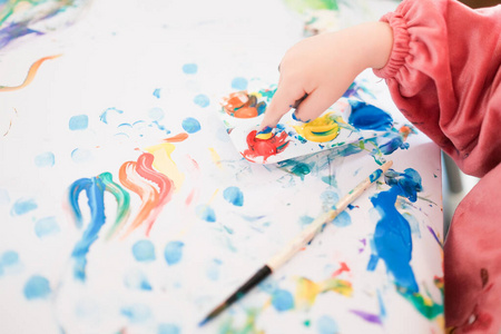一个孩子正在用手指刷子和油画颜料画画