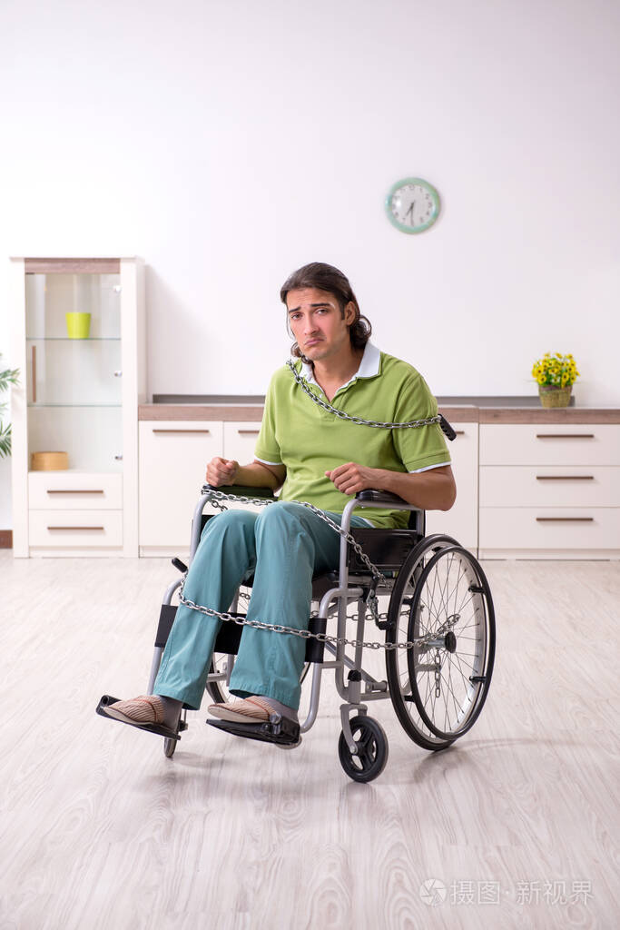 年轻男性残疾人在轮椅上受苦在家