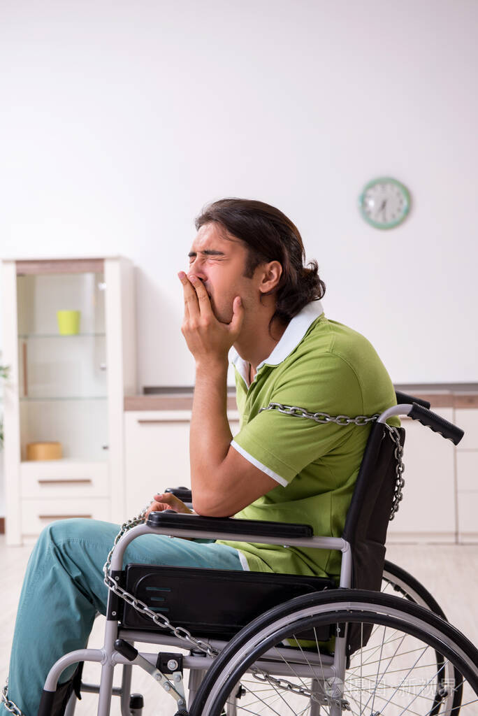 年轻男性残疾人在轮椅上受苦在家