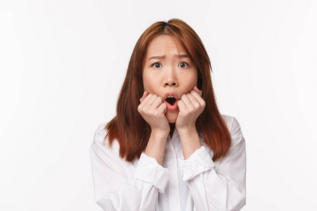咬紧牙关特写镜头:惊恐胆小的亚洲女孩惊慌失措,咬紧牙关的手指看着