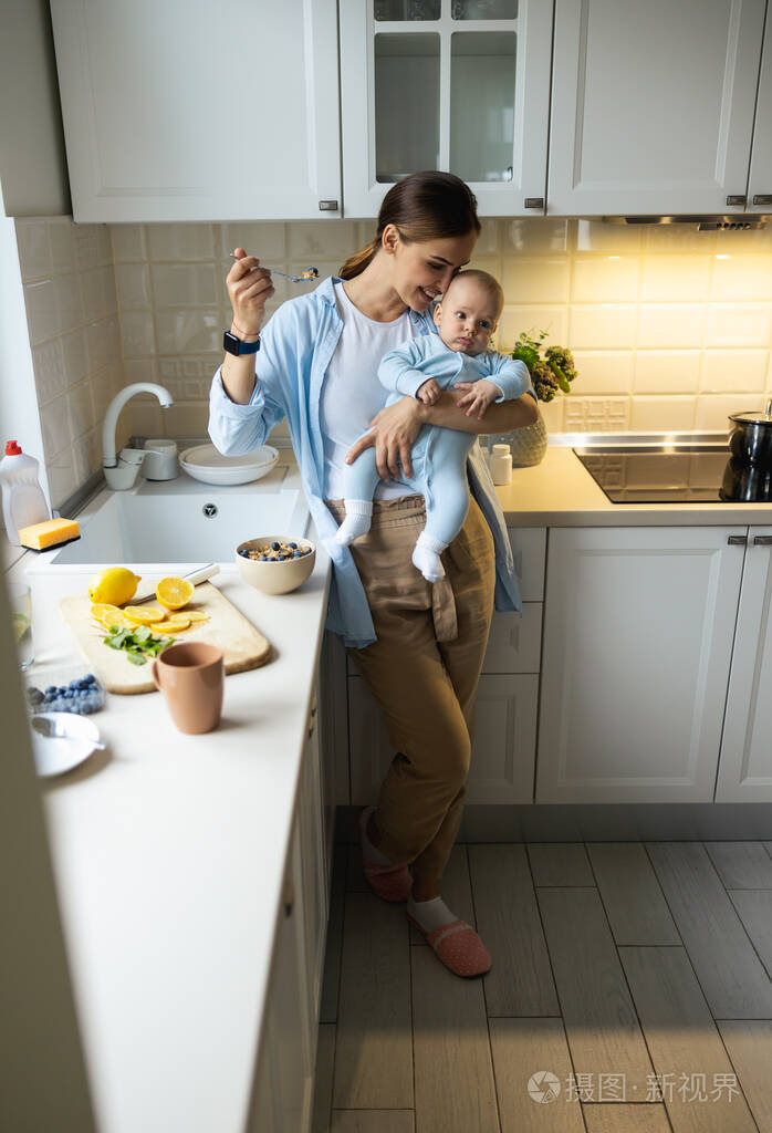 微笑美丽的妈妈抱着孩子吃燕麦粥