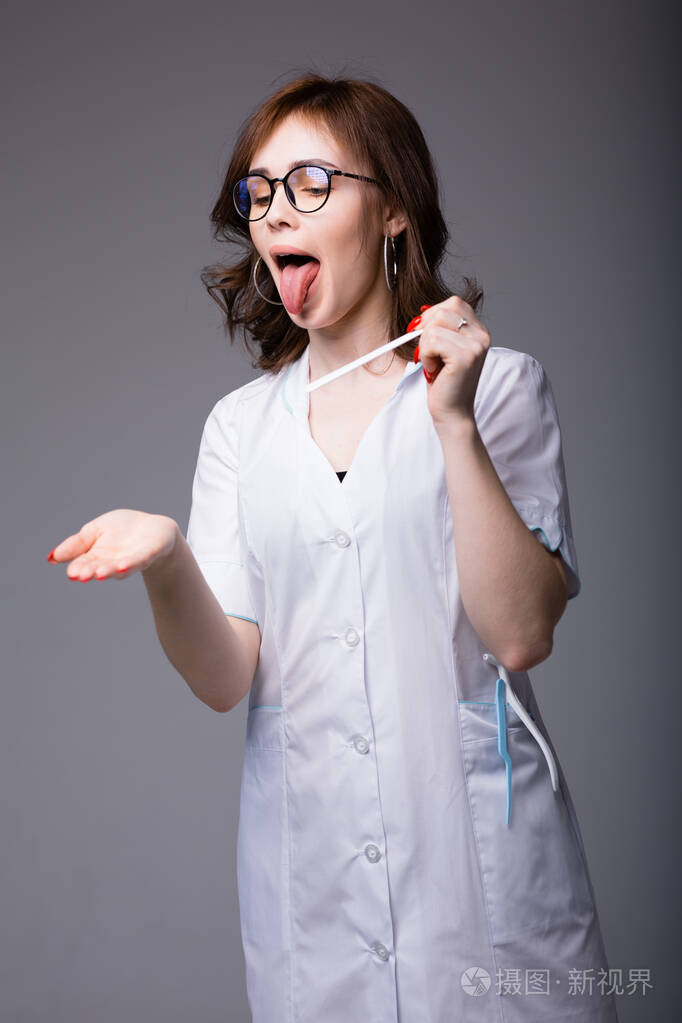 年轻的女医生伸出舌头教病人如何用检查工具把舌头伸出来