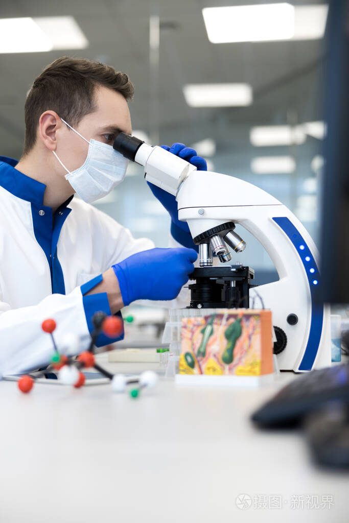 年轻研究人员在实验室使用现代显微镜