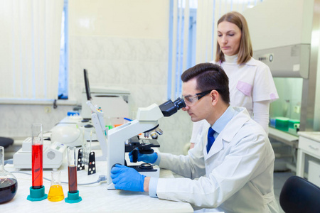 科学家在医学实验室里用显微镜进行科学研究。有助手的科学家。科维德19。冠状病毒
