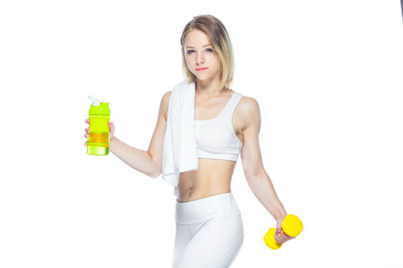 年轻漂亮的女运动员，白色背景上拿着一瓶水一条毛巾和一个哑铃