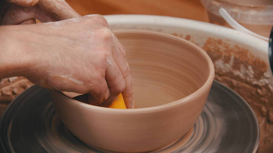 陶器这个人正在用一块黄色的海绵擦碗底