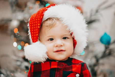 portrait of baby boy in Santa hat on Christmas tree light backgr