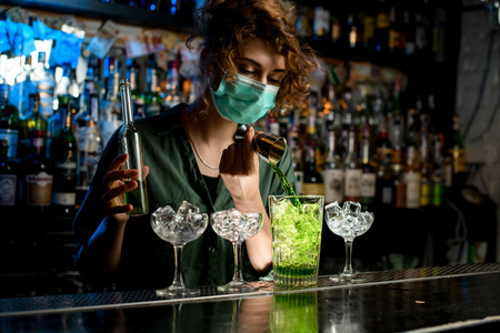女招待积极地从烧杯里把绿色液体倒进加冰的杯子里。