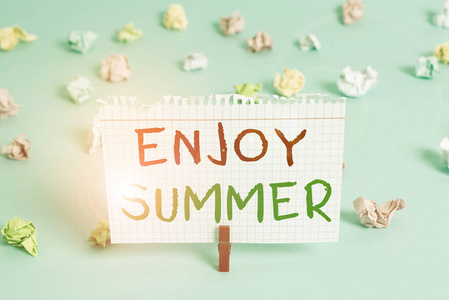 文字写作享受夏日。从学校休息和在海滩度假的商业理念彩色皱褶长方形提醒纸浅蓝色背景。