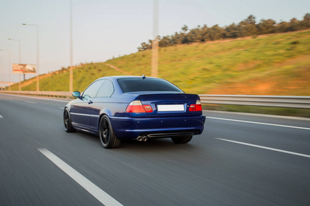 Black business class car on the highway in the sunset, red xenon