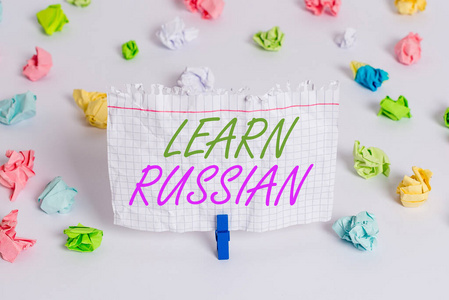 手写文字写作学俄语。概念意义获得或获得知识的说和写俄语彩色皱褶纸空提醒白色地板背景衣夹。