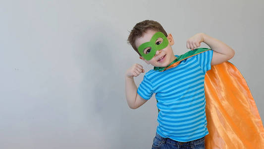 一个强壮自信的男孩在一个超级英雄服装看起来像照相机显示二头肌。成功理念。快乐的童年。
