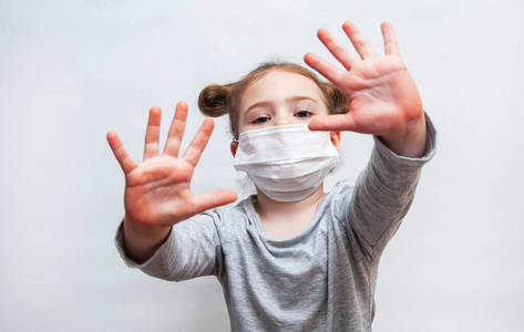 戴着一次性口罩的小女孩伸出双手.冠状病毒防疫照片