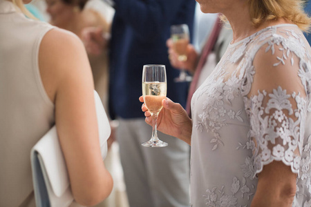 一杯香槟背景的朋友婚礼在女人手里。