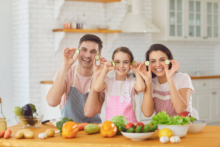 幸福的一家人微笑着坐在餐桌前，在厨房里做沙拉。