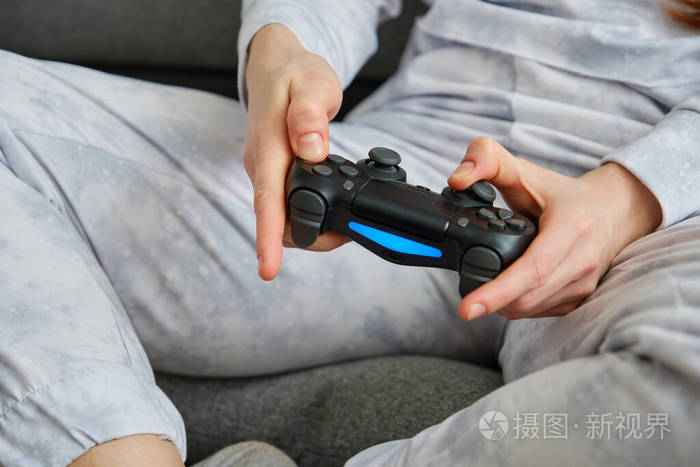 近距离拍摄一名红发女孩的手拿着游戏机坐在地上专注于双手