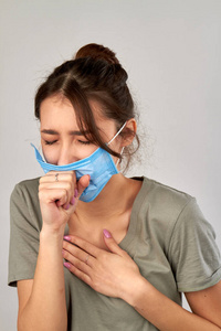 年轻女子戴着防护面具咳嗽。