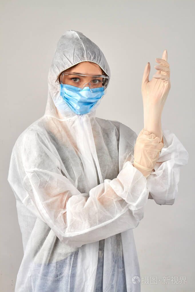 穿抗病毒防护服的女孩戴上橡胶手套