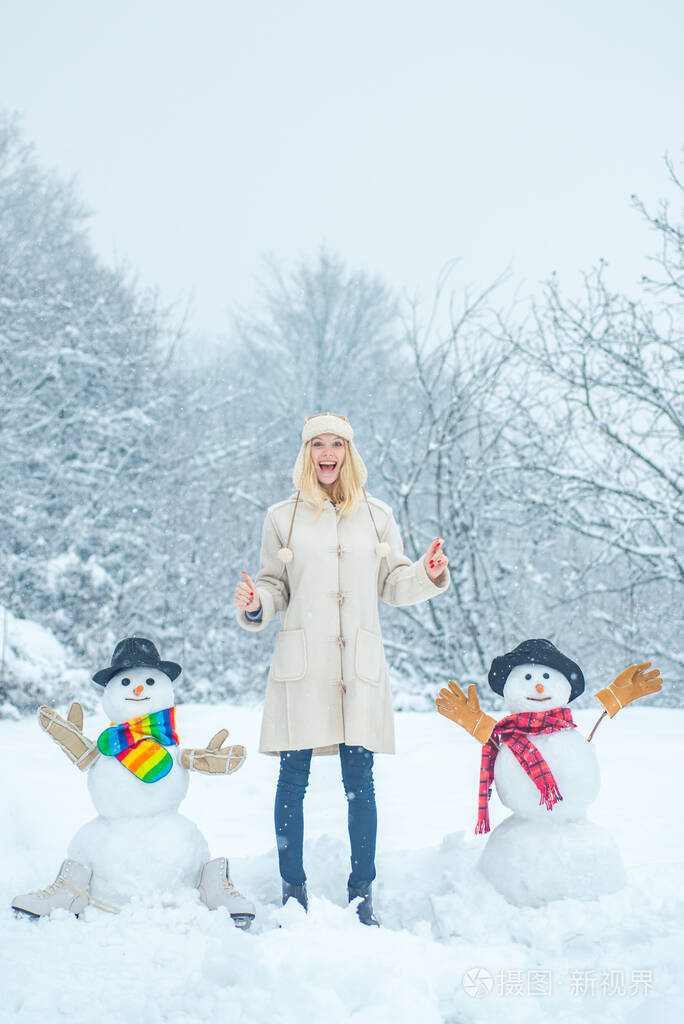 在寒冷的冬季公园里美女和雪人在一起雪地女孩雪人和滑稽的女模特站在