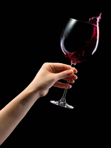 手拿酒杯一个女人手拿着红色的酒杯,溅起的水花被隔离在黑色上照片