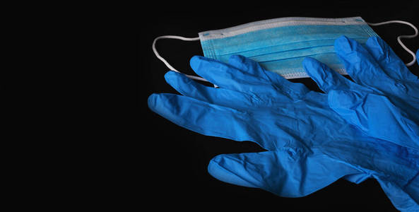 蓝色医用无菌面罩和蓝色无菌手套隔离在黑色背景上。