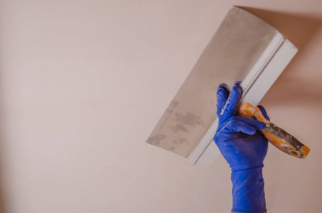 手拿着抹刀和建筑混合和平滑颠簸.修理这个墙壁.灰泥用油灰刀刮墙.