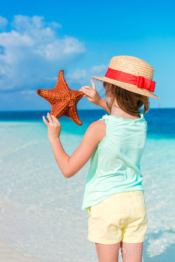 可爱的小女孩和海星在白色的沙滩上