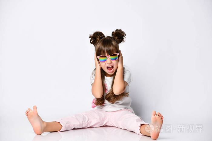 女孩的姿势坐在地板上在工作室戴着太阳镜和时尚的发型赤脚