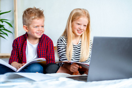 远程教育在线教育。男生和女生在家里用数码平板电脑笔记本电脑学习，做学校作业。坐在床上拿着培训书。