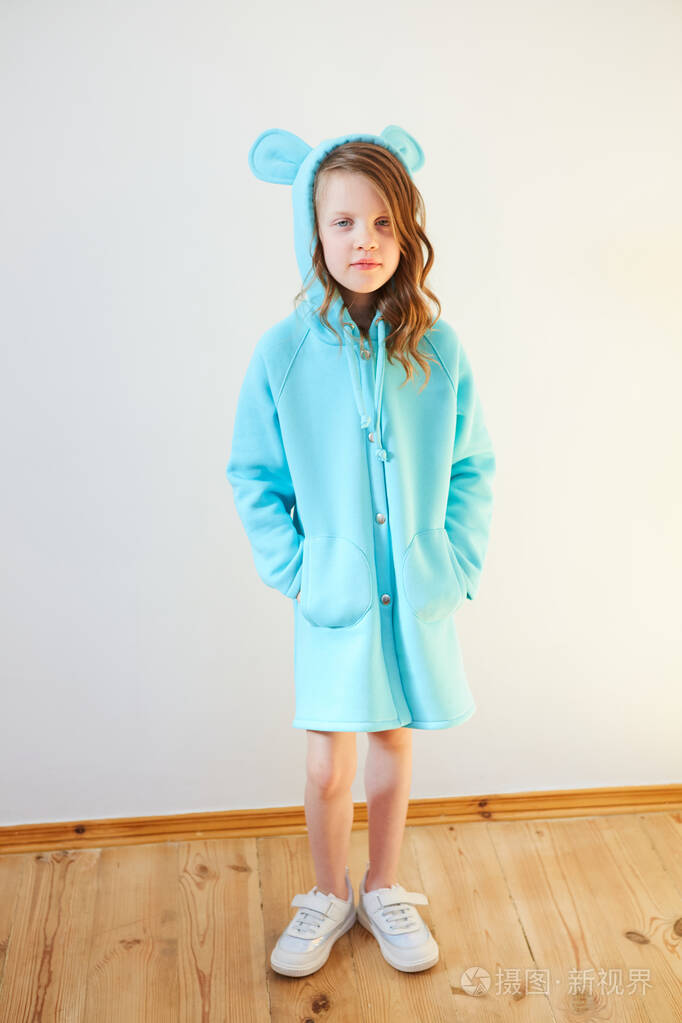 美丽的七岁女孩站在一堵白色的墙上微笑着儿童时尚春天的风格