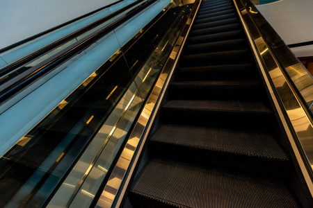 反光灯带玻璃栏杆和金色反光灯的自动扶梯.现代建筑.照片
