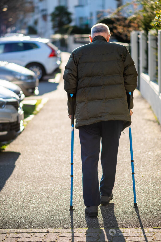 老年男性在街上使用手杖行走的后视图
