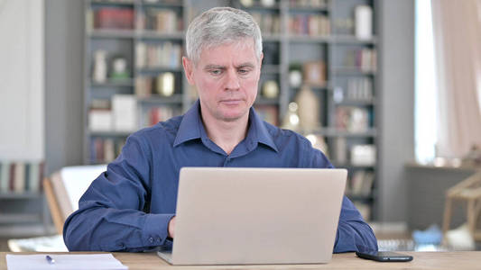 严肃的中年男人在用笔记本电脑工作